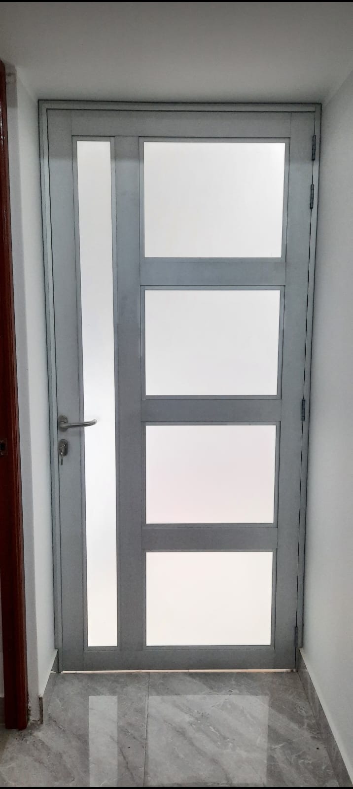 Puerta de aluminio natural con vidrios arenados de 6 mm con marco grueso